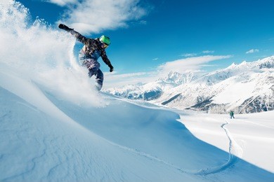 snowboarder is riding with snowboard from powder snow hill or mountain very fast