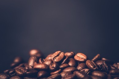 brown roasted coffee beans, seed on dark background. espresso dark, aroma, black caffeine drink. closeup isolated energy mocha, cappuccino ingredient.