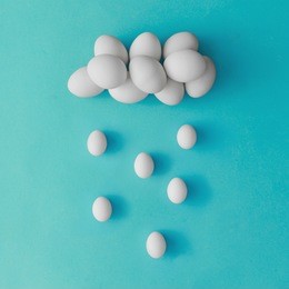 cloud and rain made of easter eggs on blue background. flat lay. minimal concept.