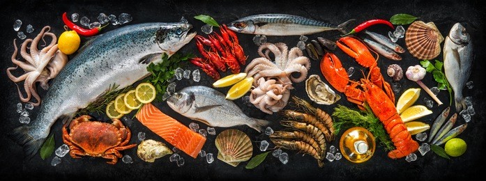 fresh fish and seafood arrangement on black stone background