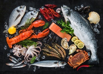 fresh fish and seafood arrangement on black stone background