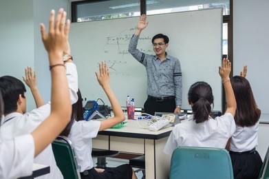 asian teacher giving lesson to group of college students which show hand for answer the question in the laboratory classroom, university education concept