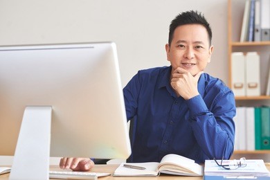 smiling asian financial manager working on computer in office