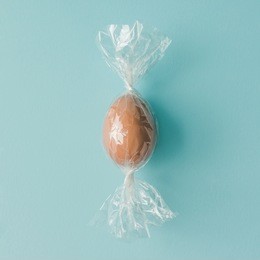 egg wrapped like candy on bright blue background. minimal easter concept.