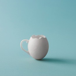 egg shell coffee cup on pastel blue background. minimal easter concept.