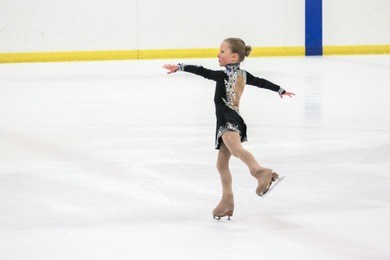 little girl figure skating at the indoor ice arena.