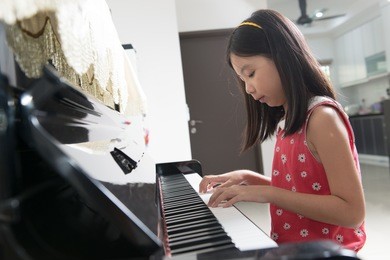 little asian girl playing piano at home