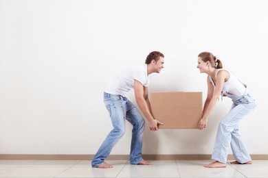 young smiling couple carries a box