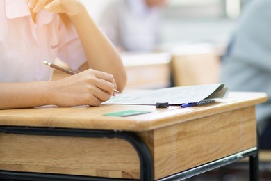 students writing test exam on paper for admissions in high school with uniform student in school classroom of thailand, exam student background and education concept: education concept
