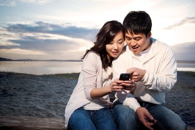a shot of an asian couple on the phone reading text messages