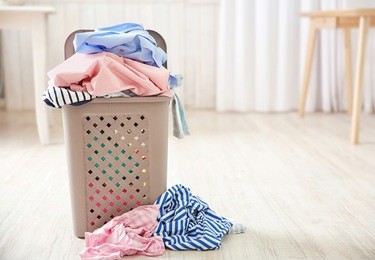 pile of clothes in plastic laundry basket indoors