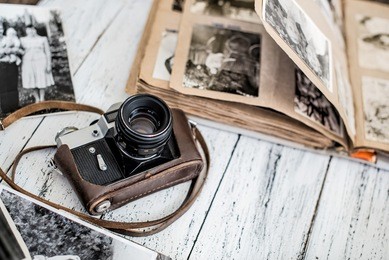 an old film camera and family album on a white wooden background among vintage family photos
