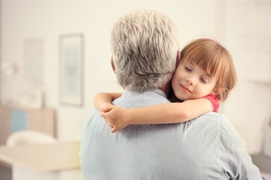 girl embracing grand father at home