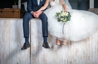 beautiful wedding couple sitting on wooden pier, swung their legs and enjoying wedding.