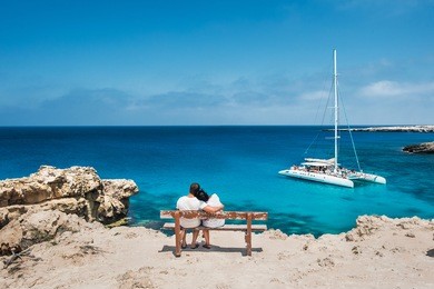 loving couple sitting on a bench and looks at the lagoon