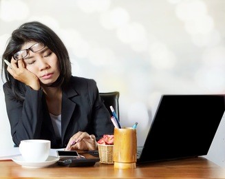  young attractive asian business woman sleeping, drowsing or taking a nap at her desk.