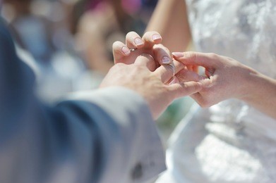 bride putting a wedding ring on groom's finger