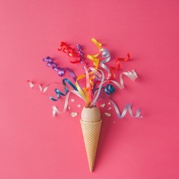 ice cream cone with egg and party streamers on pink background. minimal food concept. flat lay.