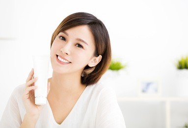 smiling young woman showing skincare products