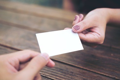 businessman giving  business card to businesswoman with wooden table background