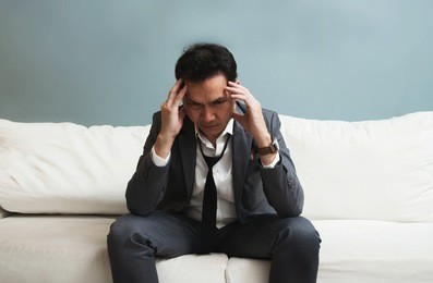 exhausted, illness, tired, stressed from overworked concepts. businessman in grey suit has headache from migraine.