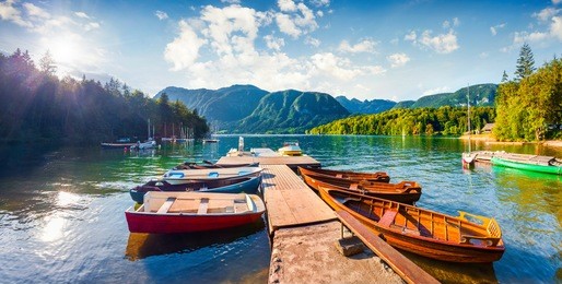 colorful summer panorama of the bohinj lake. picturesque moning scene in the triglav national park, julian alps, slovenia. popular tourist leisure on the boat. artistic style post processed photo.
