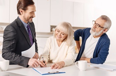 delighted real estate agent working with elderly couple of customers