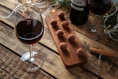 red wine, chocolate dessert and christmas decorations on wooden table