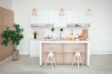 interior of small white kitchen with fresh fruit, two glasses of orange juice, baguette, red caviar, croissant and cookies with chocolate chips on the table