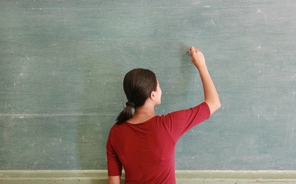 asian teacher writing on blackboard with chalk in classroom, educations concept.