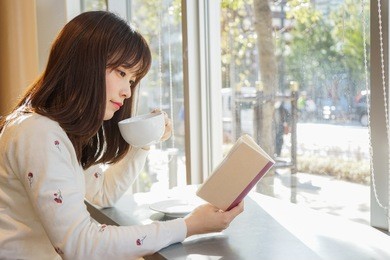 young woman reading a book at cafeteria
