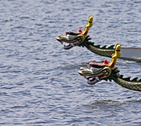 two dragon boats race neck and neck (with focus on foreground boat).