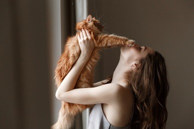 young woman in nightie which playing with cat in home