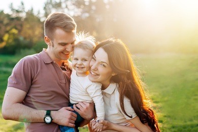 young happy family walking outdoor. parents hold child on hands and rejoice. they are happy together. smile each other