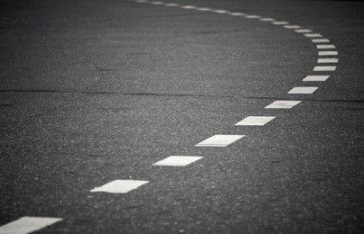 turning asphalt road with marking lines. close up photo