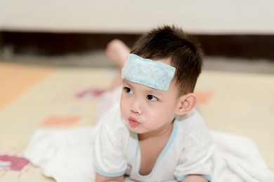 asian boy having fever . the kid attach cooling gel pad on his forehead for relief fever