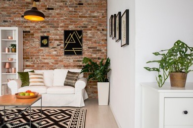 elegant room with brick wall, table, couch and green plants