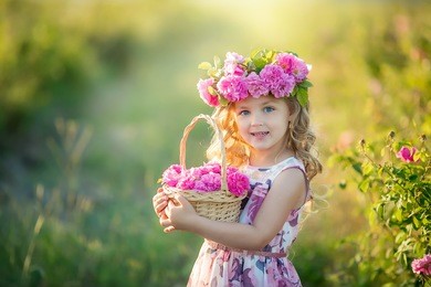 a little girl with beautiful long blond hair, dressed in a light dress and a wreath of real flowers on her head, in the garden of a tea rose
