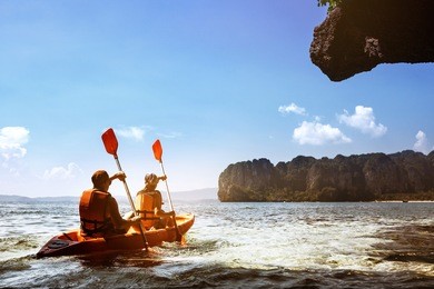 couple canoeing or kayaking at sea island backdrop. krabi province, thailand. space for text