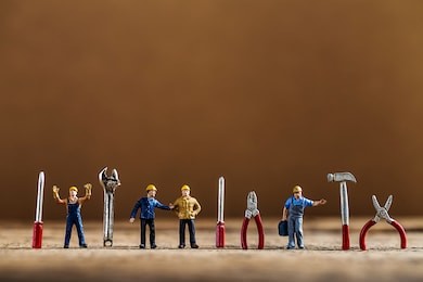 selective focus of miniature worker working with tool tools supplies and tiny home model  on wooden floor,macro photography concept idea for solution of property management service.