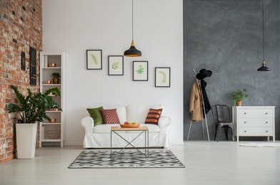 grey and white loft interior with couch, dresser and chair