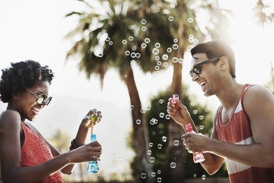 two people blowing bubbles using bubble wands