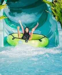 asian child play water by slider down to the swimming pool, kid in summer concept.