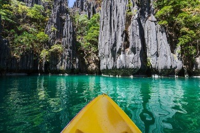 kayak in the island lagoon between mountains. kayaking journey in el nido, palawan, philippines.