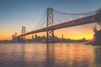 classic panoramic view of san francisco skyline with famous oakland bay bridge illuminated in beautiful golden evening light at sunset in summer, san francisco bay area, california, usa