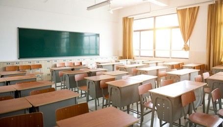 empty classroom with chairs, desks and chalkboard.