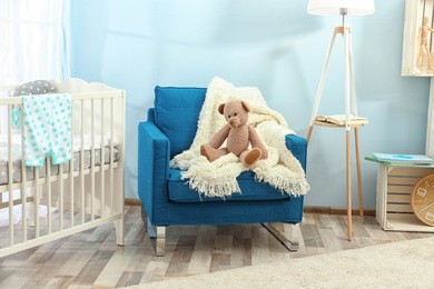 cute teddy bear on blue armchair in baby room