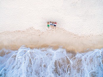 top view of group of happy friends lying on the beach near the stormy sea and dreaming. aerial view two couples relax on the beach.