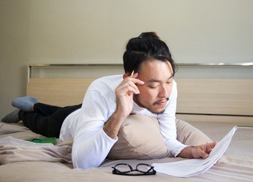 young asian man reading on the bed, concept lifestyle in bedroom.