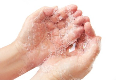 wash your hands ~ closeup of hands covered in soap suds, over white.  a cleanliness message.